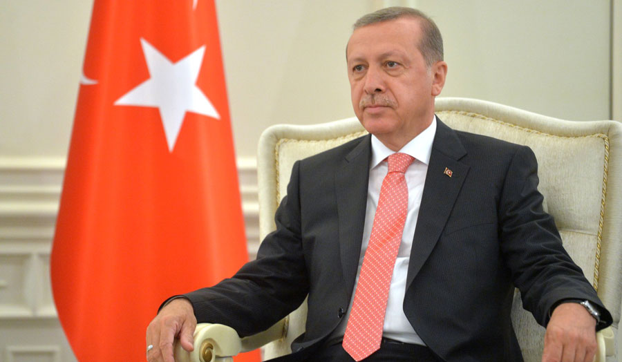 President Erdogan sitting in front of Turkish flag